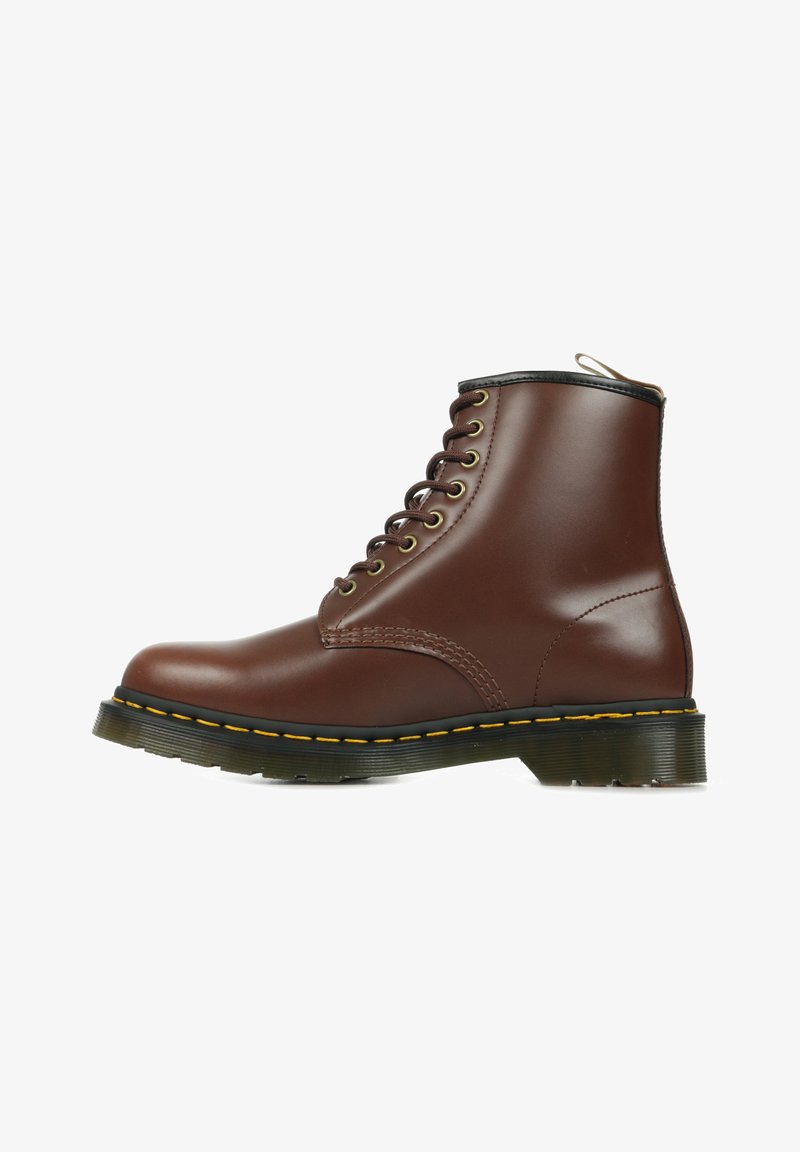 Stivale alla caviglia in pelle marrone con punta tonda, dettagli neri, cuciture gialle e suola spessa e testurizzata. Presenta occhielli metallici e design con lacci.