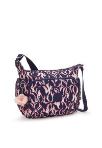 Crossbody taske med et abstrakt mønster i marineblå, lyserød og hvid, frontlomme med lynlås, justerbar rem og vedhæftet lyserød plys nøglering.