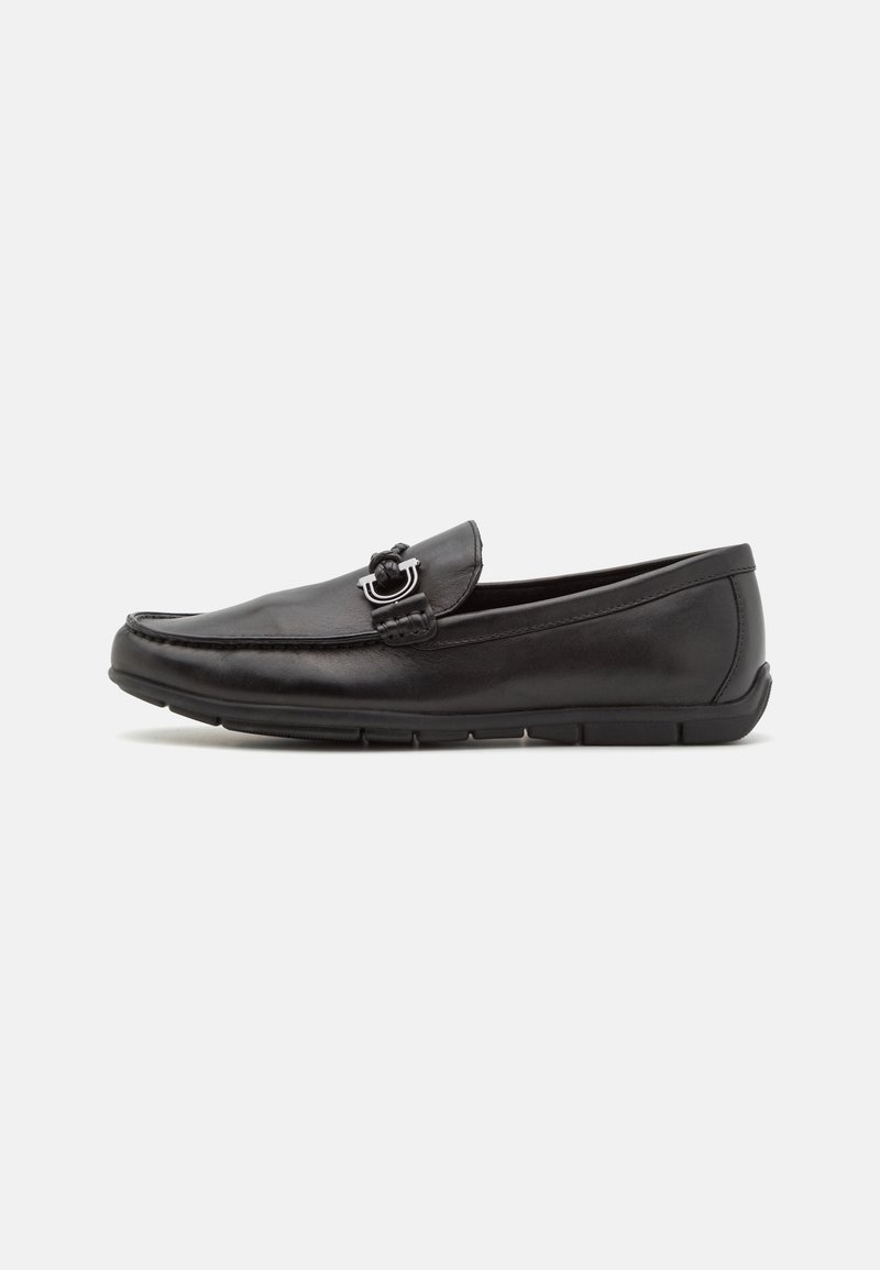 Mocassin en cuir noir avec détail mors argenté et semelle en caoutchouc basse, vu de côté sur fond blanc.