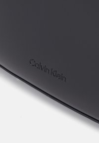 Calvin Klein REFINED SCULPT BAG SHINY - Bolso de mano - black