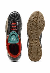 Baskets de sport noires avec une finition brillante, lacets rouges, langue turquoise, accents orange et semelles en caoutchouc texturé avec des motifs ovales.