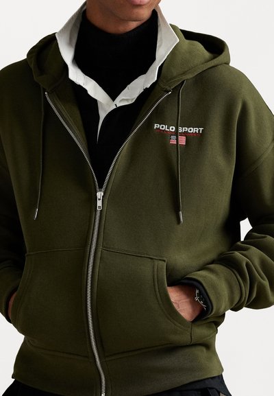 Olive green zip-up hoodie made of soft fabric, featuring a front logo "POLO SPORT," two side pockets, and a relaxed fit with drawstring hood.