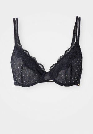 Soutien-gorge en dentelle noire avec un tissu transparent orné de motifs à pois dorés, des bords festonnés, des bretelles réglables et un accent en matériau doré.