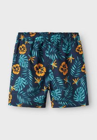 Bañador de marina con cintura elástica, que presenta vibrantes patrones tropicales de flores y hojas en naranja y verde azulado. La textura es suave y ligera.