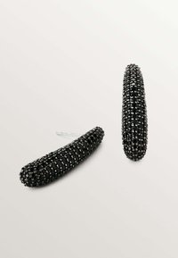 Pinzas de cabello negras, de forma ovalada, texturizadas con pequeñas cuentas negras como adorno, con una bisagra de metal plateada brillante.