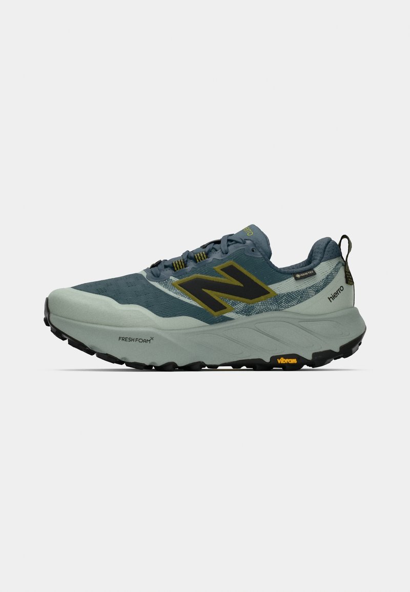 Men's trail running shoe in light gray and navy blue mesh with black rubber sole. Features yellow accents and a prominent "N" logo.