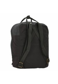Mochila con una parte superior de fieltro gris oscuro y un fondo de nylon negro. Presenta correas ajustables y un clip de metal. Diseño estructurado con acentos mínimos.