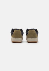 Sneaker in suede marrone e mesh blu con suola in gomma beige, caratterizzati da un classico design low-top e colletto imbottito.