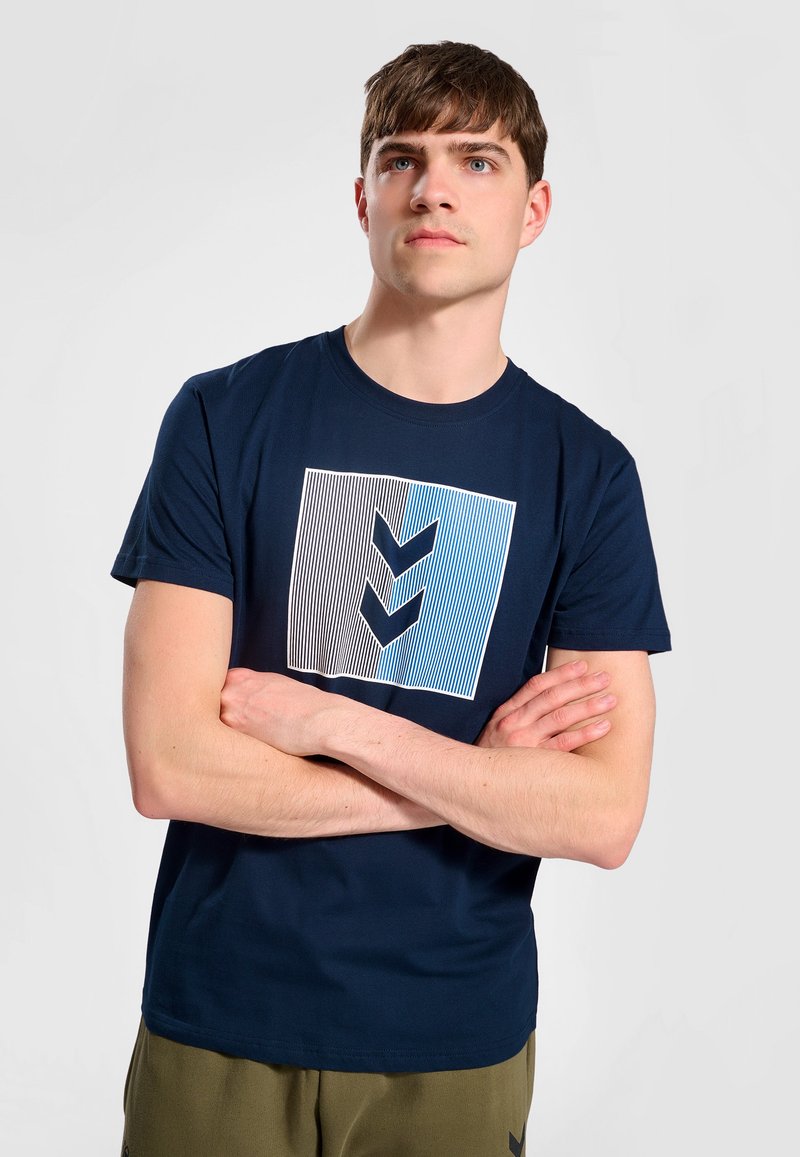 Marineblaue Baumwoll-T-Shirt mit einem grafischen Design aus Linien und Chevron-Formen in Blau- und Weißtönen. Kurze Ärmel, Rundhalsausschnitt.