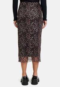 Leopardprint midi rok met een semi-doorzichtige stof, een aansluitend ontwerp en een golvende zoom, gecombineerd met zwarte chunky schoenen.