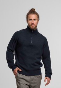 Dark navy wool sweater with a high collar and half-zip closure. Features ribbed cuffs and hem, offering a cozy, textured appearance.