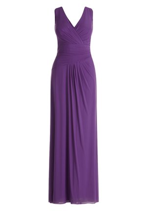 Mouwloze paarse avondjurk met V-hals, geraffineerde taille, vooraan een split, gedragen met zilveren open-toe hoge hak sandalen, gedragen door een staande vrouw.