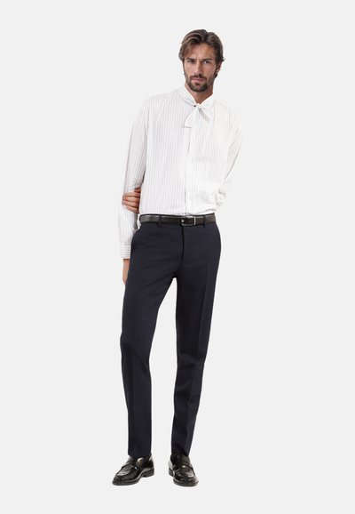 Wit gestreept overhemd met lange mouwen en een strikdas-kraag, gecombineerd met donkerblauwe broek en zwarte schoenen, met een slim fit ontwerp.