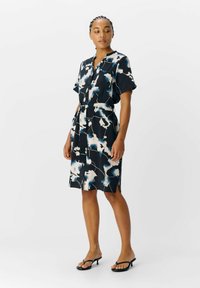 Robe noire à manches courtes avec un motif floral bleu et blanc, avec un devant à boutons, une taille ceinturée et des fentes latérales. Texture de tissu lisse.