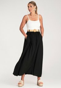 Schwarze Maxiröhre mit einem elastischen Bund, kombiniert mit einem weißen, figurbetonten Tanktop. Getragen mit einem geflochtenen Gürtel und Espadrilles mit Plattform.