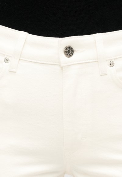 Κοντινή λήψη της μέσης ενός λευκού τζιν από denim με μεταλλικό κουμπί και θηλιές για ζώνη μπροστά σε μαύρο φόντο.