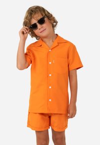 Camisa de manga corta naranja con cuello, botones en la parte delantera y bolsillo, acompañada de pantalones cortos a juego. Textura suave y color brillante.