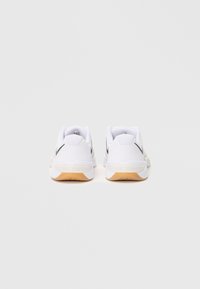Pair of white Nike Metcon sneakers with black swoosh logos viewed from the back on a plain light background.