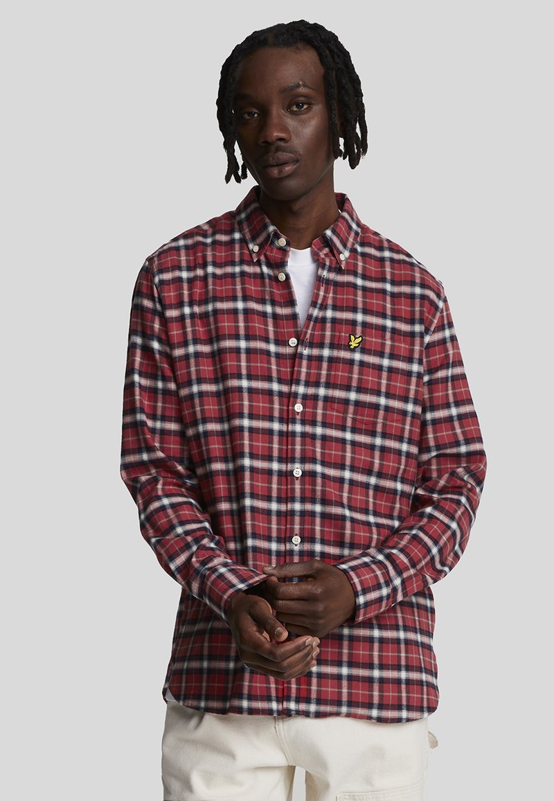 Camicia a quadri rossa e blu navy con colletto button-down, maniche lunghe e bottoni bianchi. Presenta un piccolo logo giallo sul lato sinistro del petto.