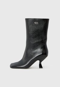 Μαύρο δερμάτινο μποτάκι μέχρι τον αστράγαλο με γυαλιστερό φινίρισμα, τετράγωνη μύτη και μοναδικό καμπυλωτό τακούνι. Διαθέτει μικρό μεταλλικό λογότυπο ως λεπτομέρεια.