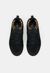 Black sneakers with a smooth finish, featuring a leopard print lining. The design includes flat laces and a padded cuff for comfort.