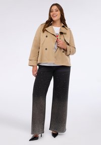 Beige dubbelknäppt jacka, svarta vida byxor medgradientdesign och rhinestones, tillsammans med svarta spetsiga klackar.