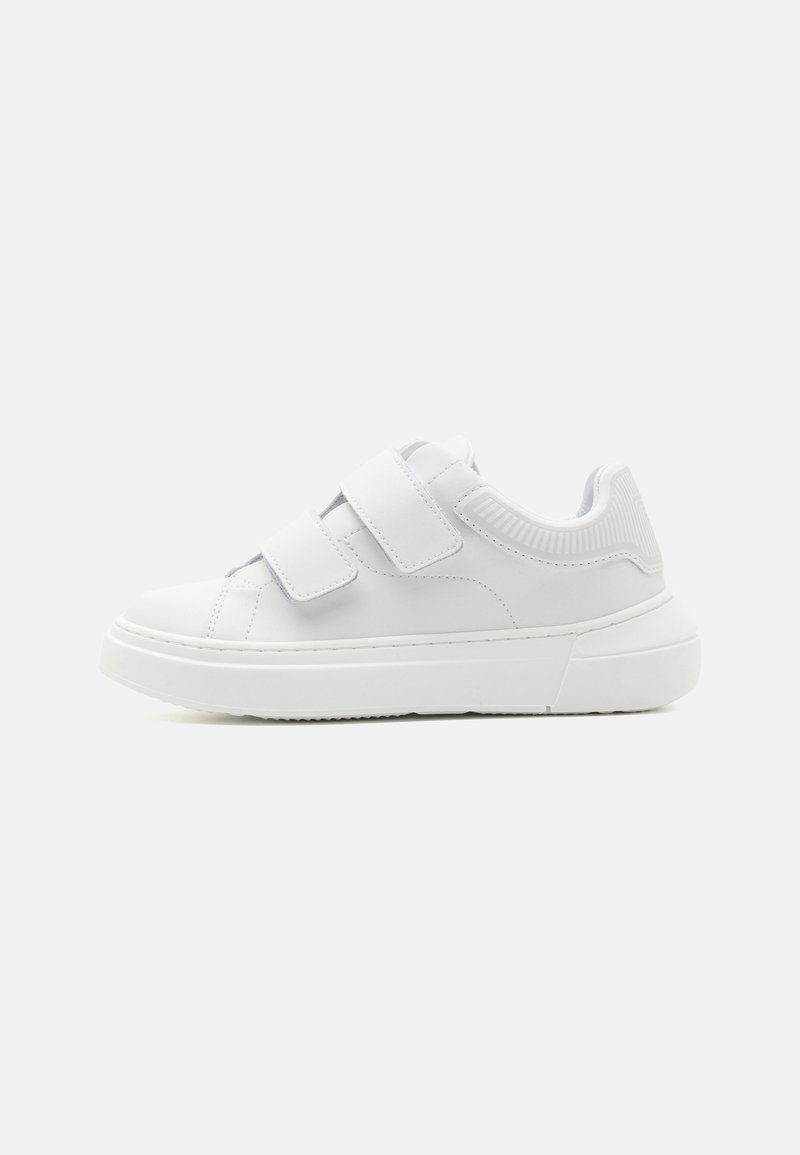 Hvite sneakers med borrelås, glatt syntetisk materiale, rund tå og tykk såle med et teksturert preg ved hælen.