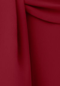 Zachte, dieprode stof met zachte plooien en een subtiel diagonaal weefpatroon dat van dichtbij zichtbaar is.