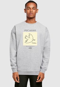 Grijze sweatshirt met een afbeelding van een duif en de tekst "PICASSO," "DE VREDESDUIF 1949," met ribgebreide mouwen en een ronde hals.