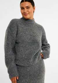 Grå strikket trøje med høj hals og lange �ærmer, lavet af et tekstureret, fluffy materiale. Designet er afslappet og let oversized.