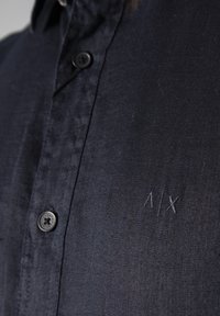 Camicia abbottonata blu navale realizzata in tessuto leggero. Presenta un discreto logo A/X ricamato sul lato sinistro del petto e un classico design del colletto.