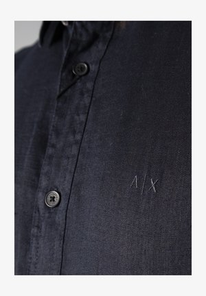 Camicia blu navy con bottoni, realizzata in tessuto testurizzato. Presenta un piccolo logo ricamato "A/X" e un colletto standard con bottoni neri.
