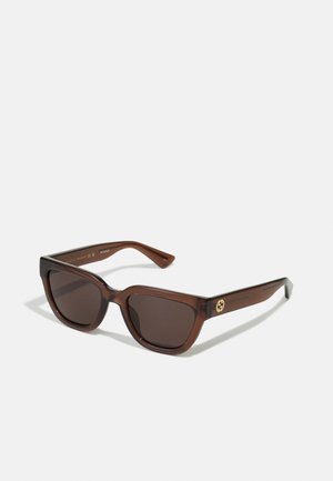 Gafas de sol rectangulares marrones con bordes redondeados, que presentan lentes oscuros y un acabado brillante. Acento de logo dorado en las patillas.
