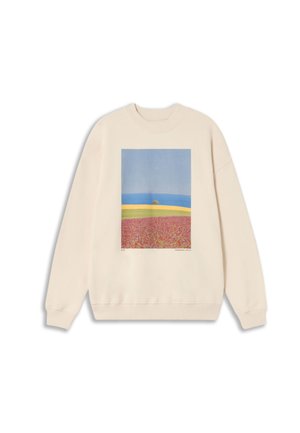 Sweatshirt crème avec un motif carré d'un paysage comprenant un ciel bleu, un océan, un champ jaune et des fleurs roses. Poignets et ourlet côtelés.