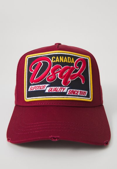 Maroon baseball cap with a rectangular patch reading "Canada Dsquared2 Superior Quality Since 1995" in red, yellow, white, and black.