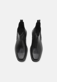 Bottines noires en cuir avec un design élégant et à bout carré. Elles présentent des panneaux latéraux élastiques et une languette pour un enfilage facile. Texture lisse.
