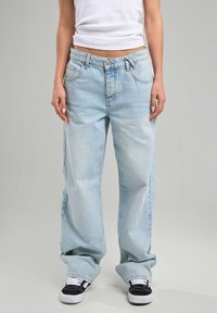 Light blue denim jeans with a relaxed fit, featuring a button closure, five pockets, and visible stitching details.