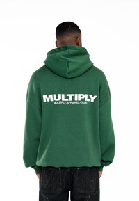 Sudadera verde de gran tamaño con un gran logotipo blanco de "MULTIPLY" en la parte posterior, con capucha ajustable y puños acanalados.