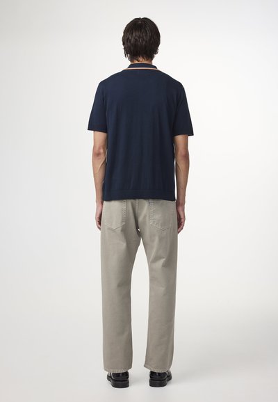 Navy-blauer kurzärmeliger Pullover mit Rundhalsausschnitt, kombiniert mit hellbeigen geraden Hosen. Einfaches und klassisches Design, ohne Muster.