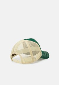 Casquette verte avec dos en mesh et accents beiges. Elle possède une visière courbée et une fermeture snapback. Couture visible le long de la visière.