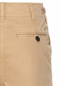 Beige Baumwollhosen mit einer Seitentasche, Knopfdetails und genähten Nähten. Glatte Textur mit einer taillierten Passform.