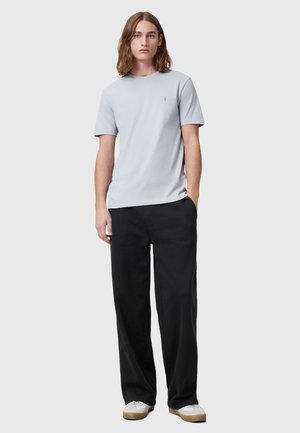Lichtblauw T-shirt met korte mouwen en ronde hals, gecombineerd met zwarte wijde broek en witte sneakers, met een ontspannen pasvorm.