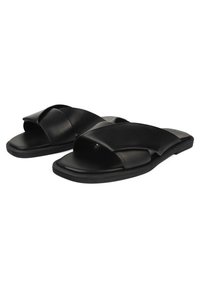Infradito in pelle nera con design a strap incrociati, suola piatta e punta aperta. Textura liscia con uno stile minimalista.