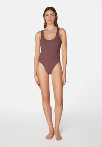 Rippierter Einteiler in dunklem Mauve, mit Rundhalsausschnitt, breiten Trägern, hohem Beinausschnitt und nahtloser Textur.