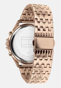 Reloj de acero inoxidable en oro rosa con una pulsera tejida texturizada y una caja redonda. Presenta un fondo pulido con grabado de la marca.