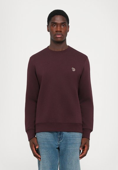 Sweat-shirt bordeaux en mélange de coton, avec un col rond et des poignets côtelés. Petit logo brodé sur la poitrine. Associé à un jean bleu clair.