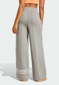 Grå vida byxor med vertikala sömmar, hög midja och randiga detaljer vid fållen. Tillverkade av mjukt tyg och har en avslappnad passform.