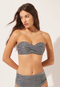 Sort og hvid strappy bandeau bikini top med en snoet frontdesign og struktureret mønster, parret med højtaljede trusser i samme stil.