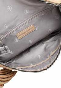 Interior de un bolso marrón con un bolsillo con cremallera, forro de tela gris con patrón de logotipos repetido y cierre superior con cremallera con herrajes negros.