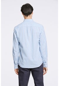 Camisa de manga larga en azul claro con rayas verticales blancas. Cuello abotonado, dobladillo redondeado y puños con botón. Hecha de una tela suave.
